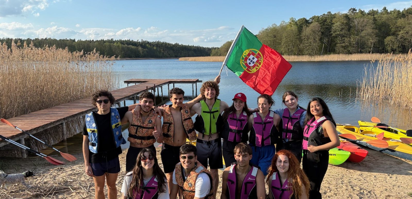 Participants holding the Portuguese flag by a lake after an afternoon of kayaking